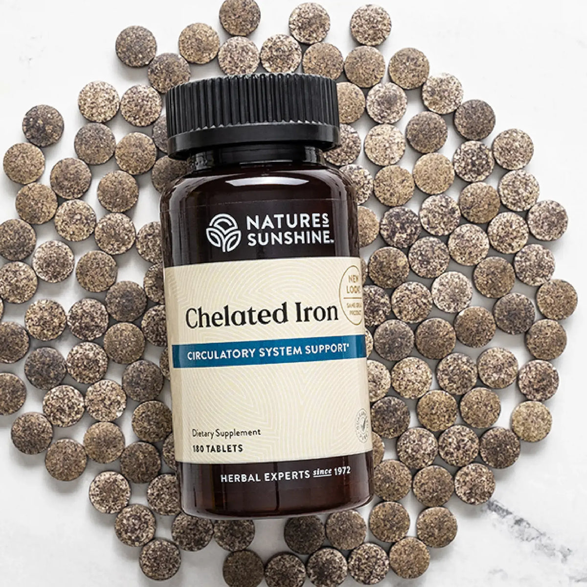 Nature's Sunshine Chelated Iron supplement bottle surrounded by iron supplements on a marble surface.