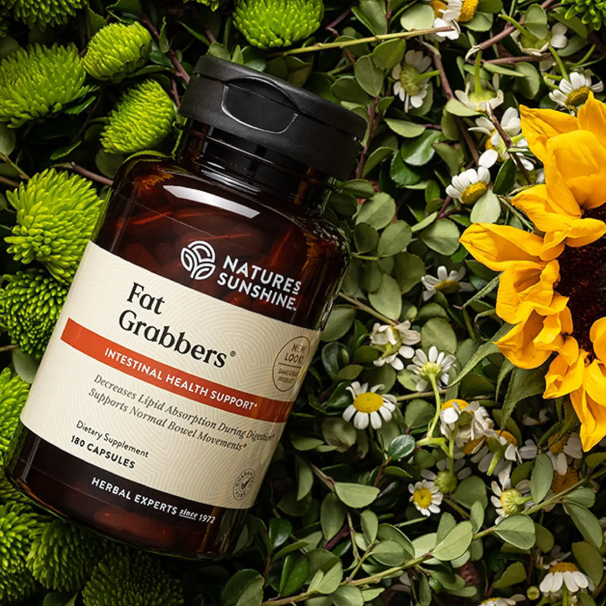 Nature's Sunshine Fat Grabbers supplement bottle on a natural background with greenery and flowers.
