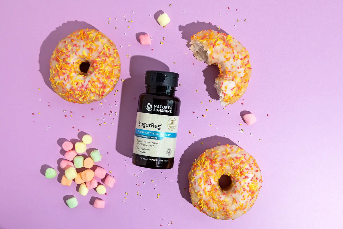 Bottle of Nature's Sunshine SugarReg on a pink background with donuts and candy.