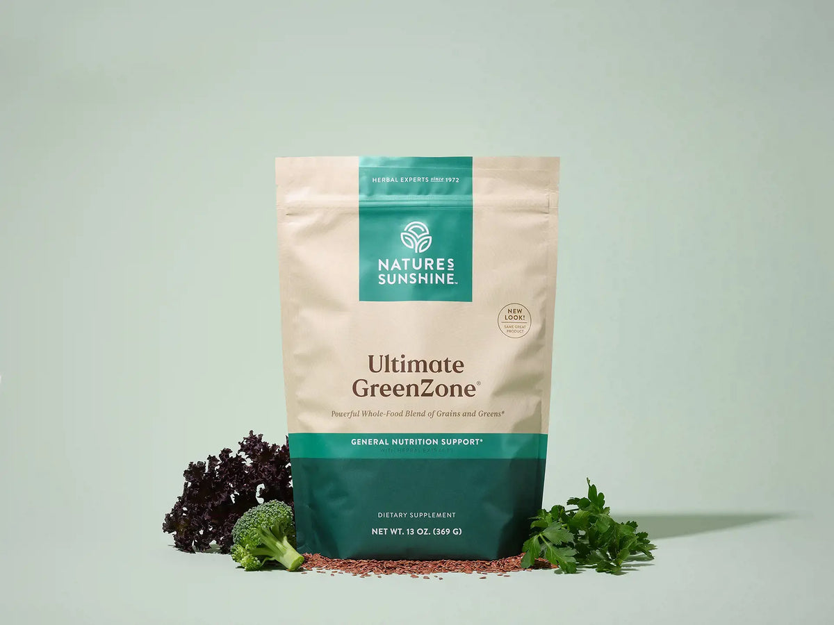Nature's Sunshine Ultimate GreenZone dietary supplement pouch, styled with broccoli, parsley, and red powder on a light sage green background.