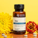 Nature's Sunshine Zinc supplement bottle with yellow flowers on a yellow background