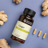 Nature's Sunshine Ginger supplement bottle with ginger root and capsules on a blue background