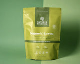 A stand-up pouch of Nature's Sunshine Nature's Harvest super-food instant beverage, shown on a solid sage green background.