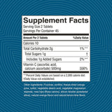 A supplement facts label shown on a blue patterned background. The label reads 'Supplement Facts' with serving size 2 tablets, calories 10, total carbohydrate 2g, total sugars 1g, includes 1g added sugars, vitamin C 556%, and lists other ingredients including fructose, sorbitol, vegetable stearic acid, vegetable magnesium stearate, rose hips, silicon dioxide, natural orange flavor, and natural lemon-lime flavor.