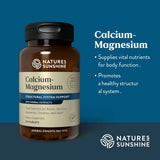 Nature's Sunshine Calcium-Magnesium dietary supplement bottle on a dark blue background with product information text on the right.