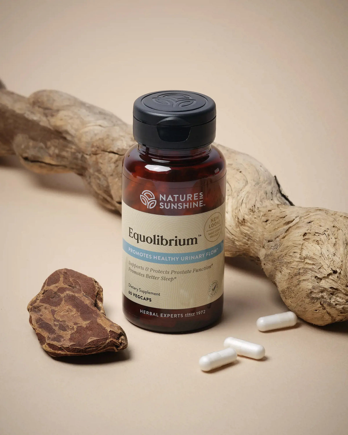 A bottle of Nature's Sunshine Equilibrium herbal supplement, flanked by natural roots and white capsules on a warm beige background.