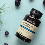 Nature's Sunshine Combination Potassium supplement bottle, 120 capsules, shown on a textured light blue background with scattered blackberries and green sprigs.