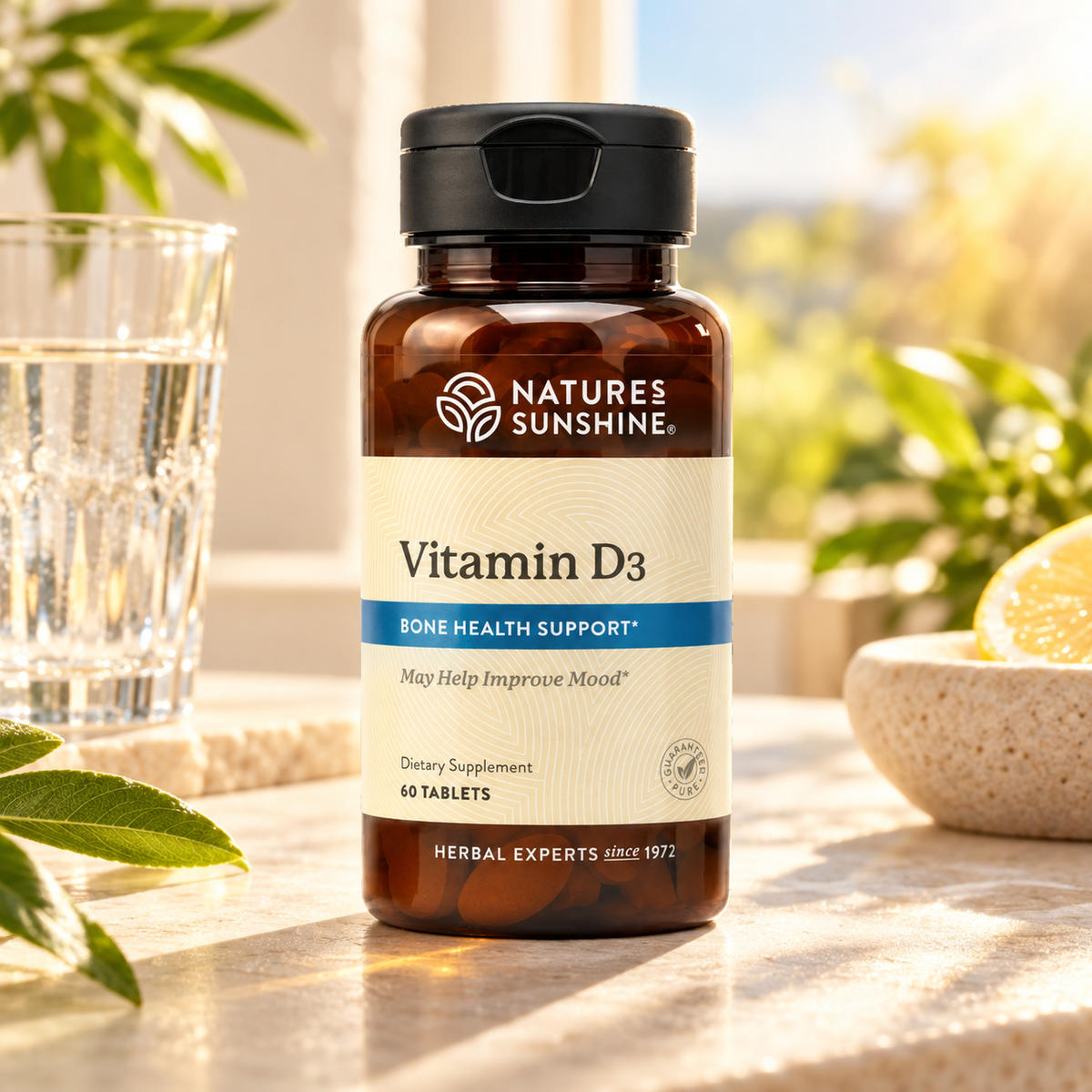 A bottle of Nature's Sunshine Vitamin D3 dietary supplement, set on a stone surface with a glass of water and lemon slices in a bright, sunny outdoor setting.