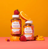 Two Nature's Sunshine MultiVitamin & Minerol bottles styled with fresh fruit on a pink and orange studio background.
