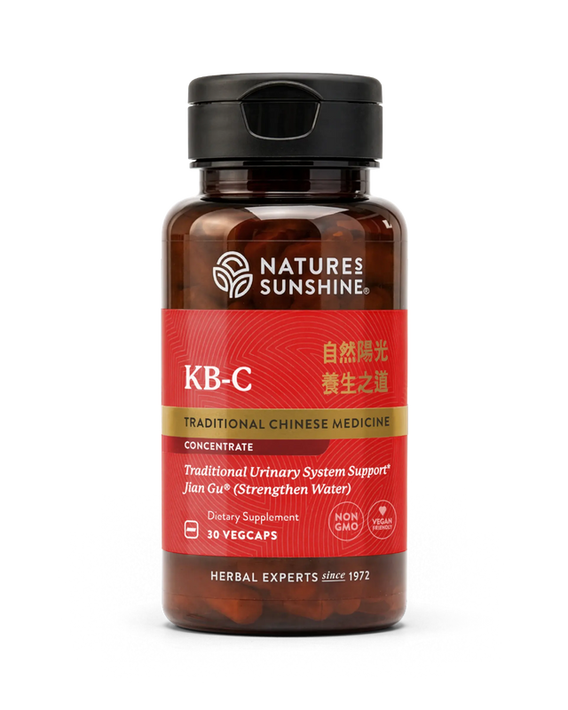 A bottle of Nature's Sunshine KB-C Traditional Chinese Medicine dietary supplement, featuring a dark amber bottle, black cap, and a red label with gold and white text.