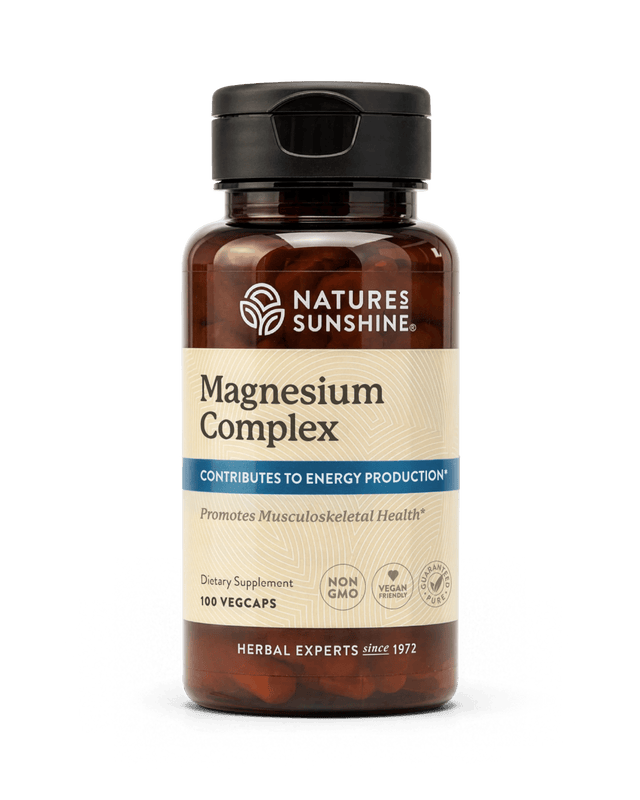 Nature's Sunshine Magnesium Complex dietary supplement bottle with a black cap and amber-brown plastic, containing 100 vegcaps, on a white background.