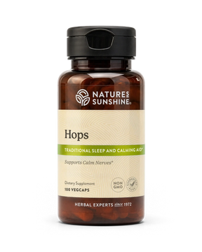 A bottle of Nature's Sunshine Hops dietary supplement with a black cap and amber-brown bottle, featuring a beige label with green accents, on a white background.