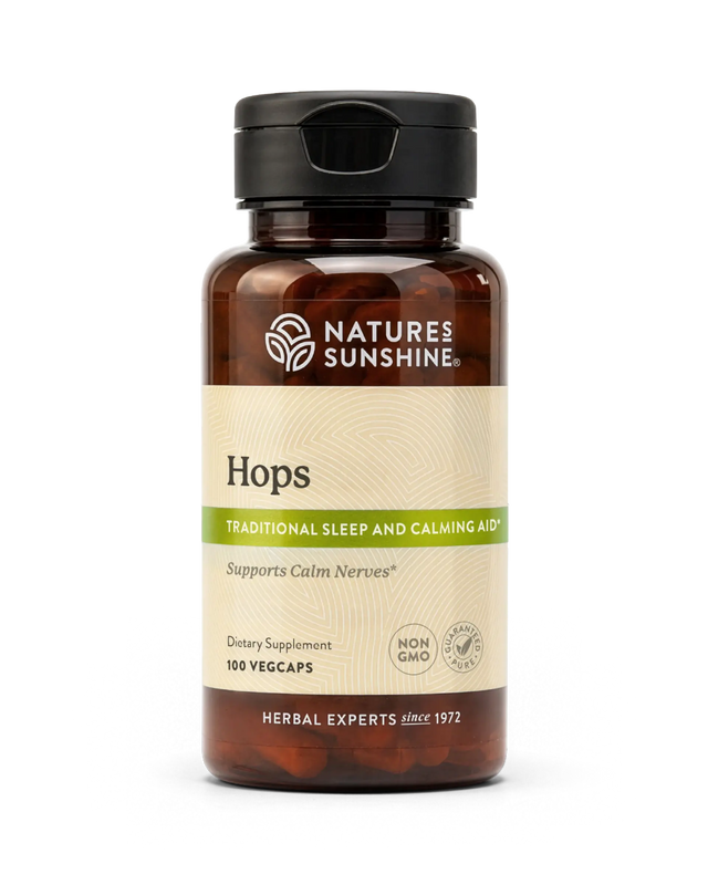 A bottle of Nature's Sunshine Hops dietary supplement with a black cap and amber-brown bottle, featuring a beige label with green accents, on a white background.