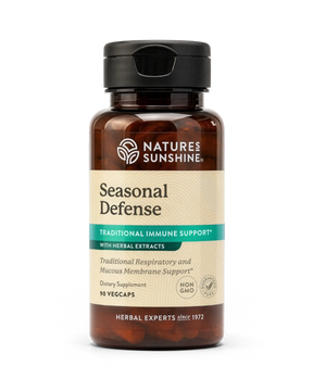 A bottle of Nature's Sunshine Seasonal Defense dietary supplement with amber brown plastic, a black cap, and a beige label with green and teal accents, shown on a white background.